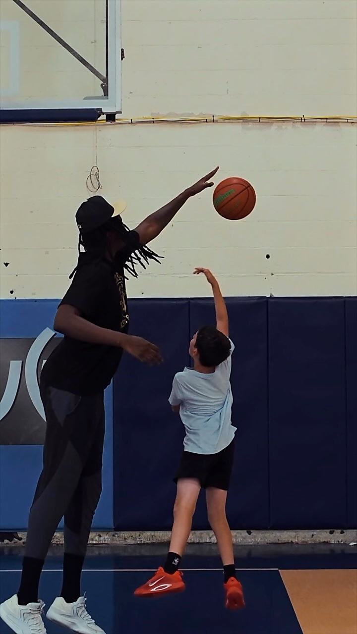 Reel: a coach challenging a young player’s shot in the gym
