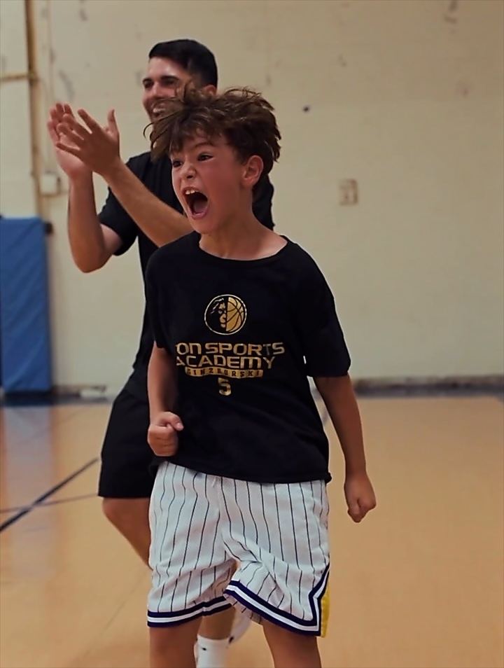 Reel: a young player celebrating with a coach at camp