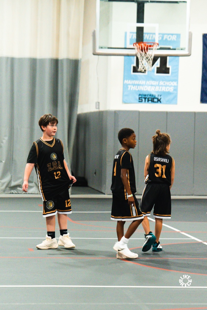 Young Zion players in black ZSA jerseys standing together on the court