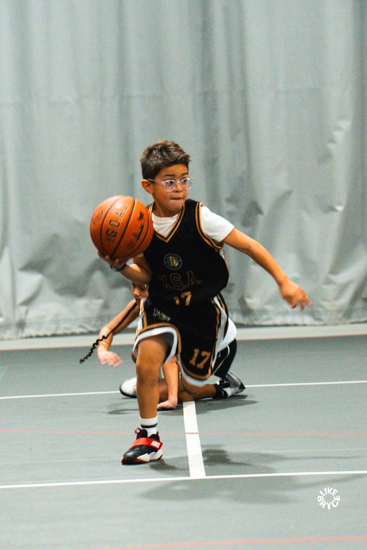 Young Zion player in glasses dribbling past a defender
