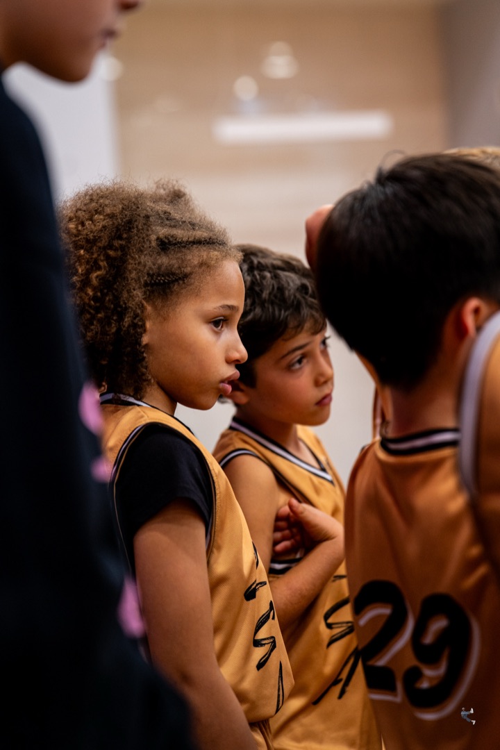 Young Zion players in gold jerseys listening closely in a team huddle