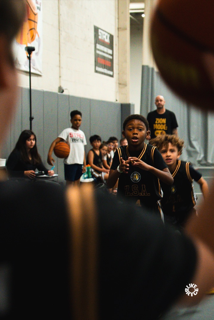 Young Zion player in a black ZSA jersey pointing downcourt during a game