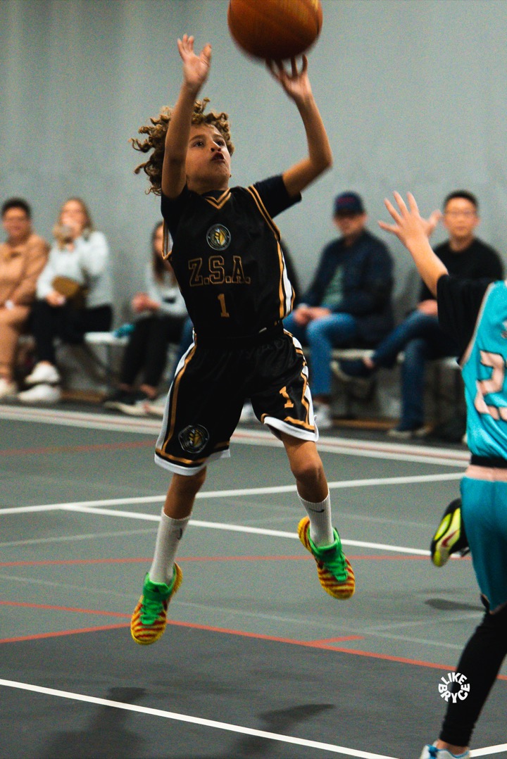 Young Zion player in a black ZSA jersey rising up for a jump shot