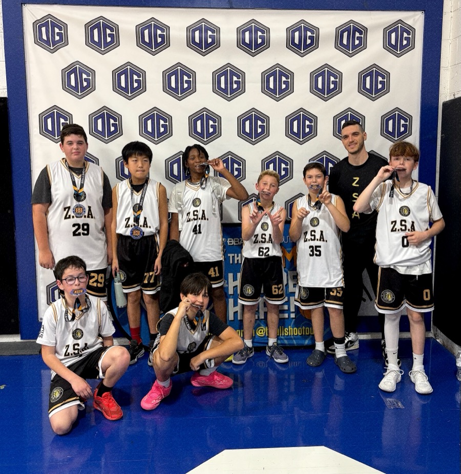 Zion Sports Academy team with medals at a tournament, posing by the step-and-repeat backdrop