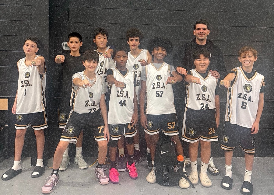 Zion Sports Academy team posing with championship rings against a dark brick wall